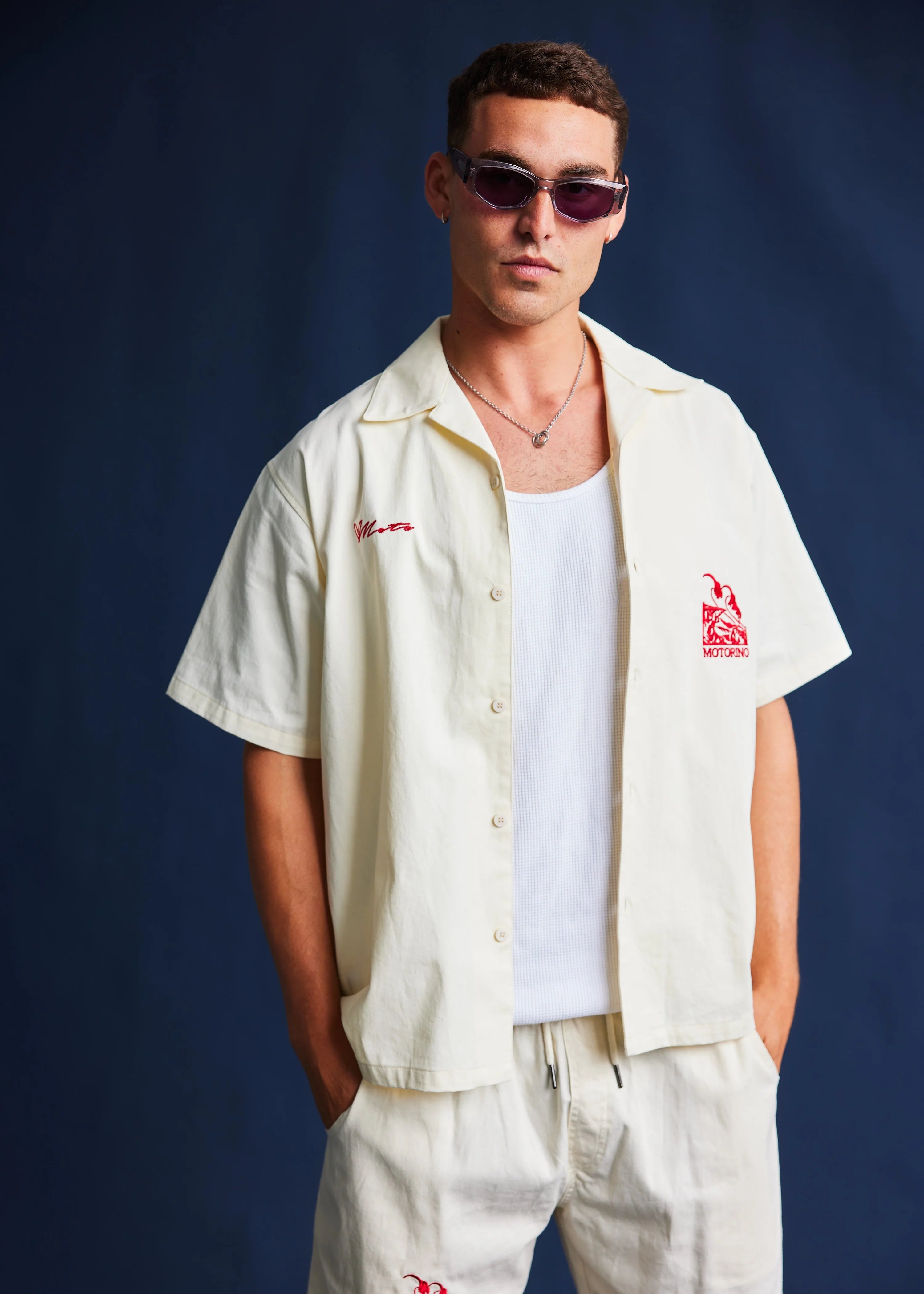 Man wearing a light-colored shirt with red logos against a dark blue background