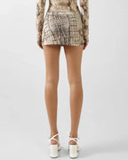 Person wearing a patterned outfit with a skirt and top on a white background