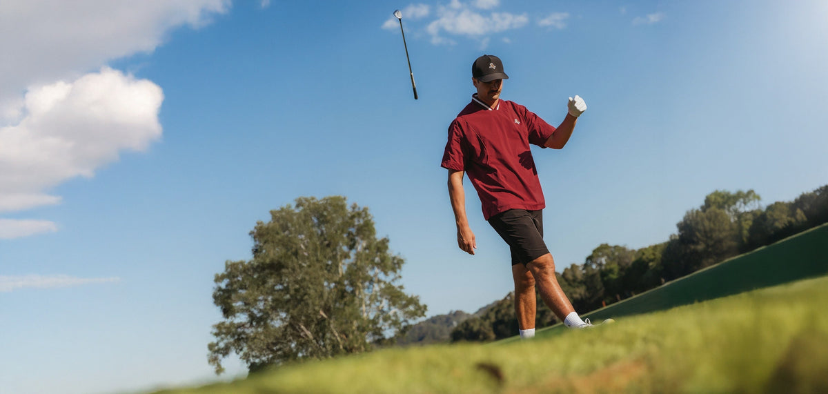 Golfer in a red Walker Golf Things top watching his club fly into a blue sky